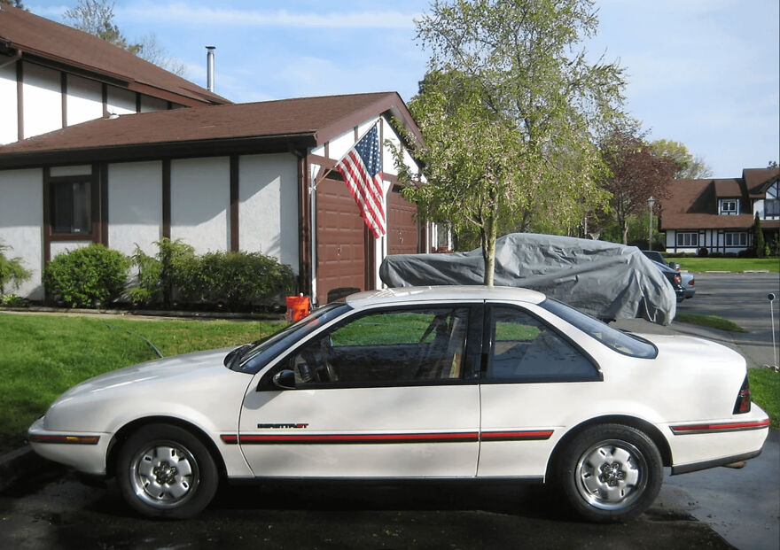 White 1980s vintage car parked in a suburban driveway showcasing classic design from the 80s era.