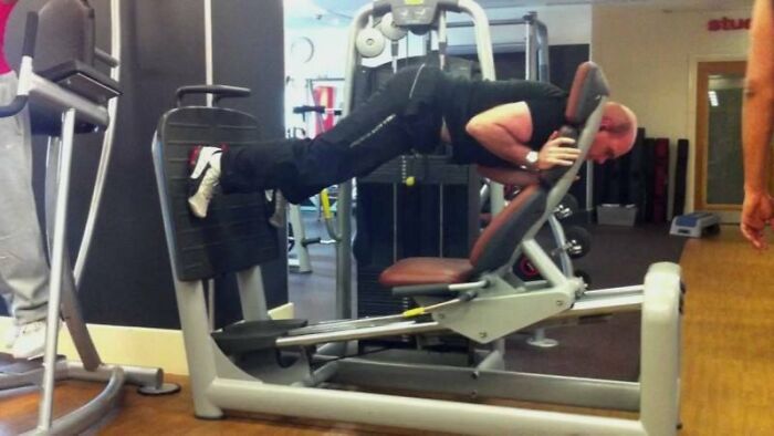Person in a gym using exercise equipment incorrectly, demonstrating a Darwin Award contender moment at the gym.