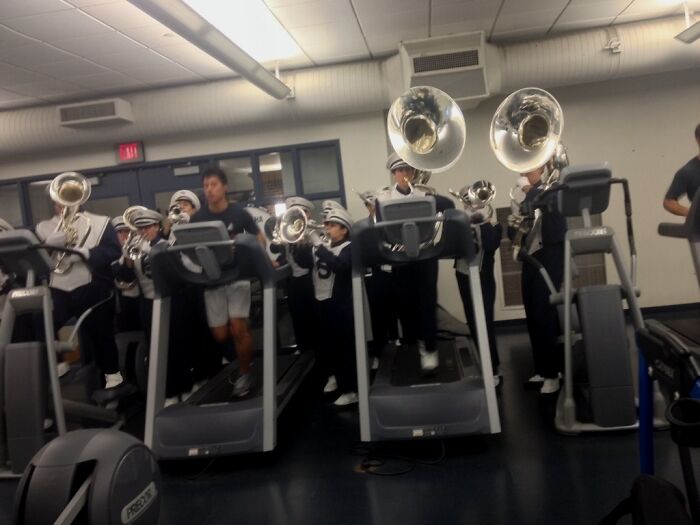 Marching band members playing instruments while walking on gym treadmills, a surprising gym moment.