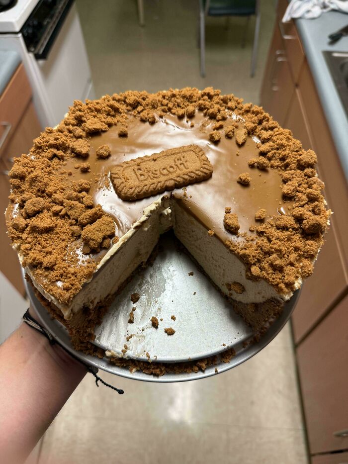 Lotus biscuit cheesecake with a slice removed, topped with crushed biscuits