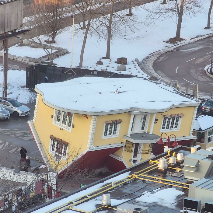 An upside-down yellow house covered in snow, a bizarre sight making viewers want to fix things immediately.