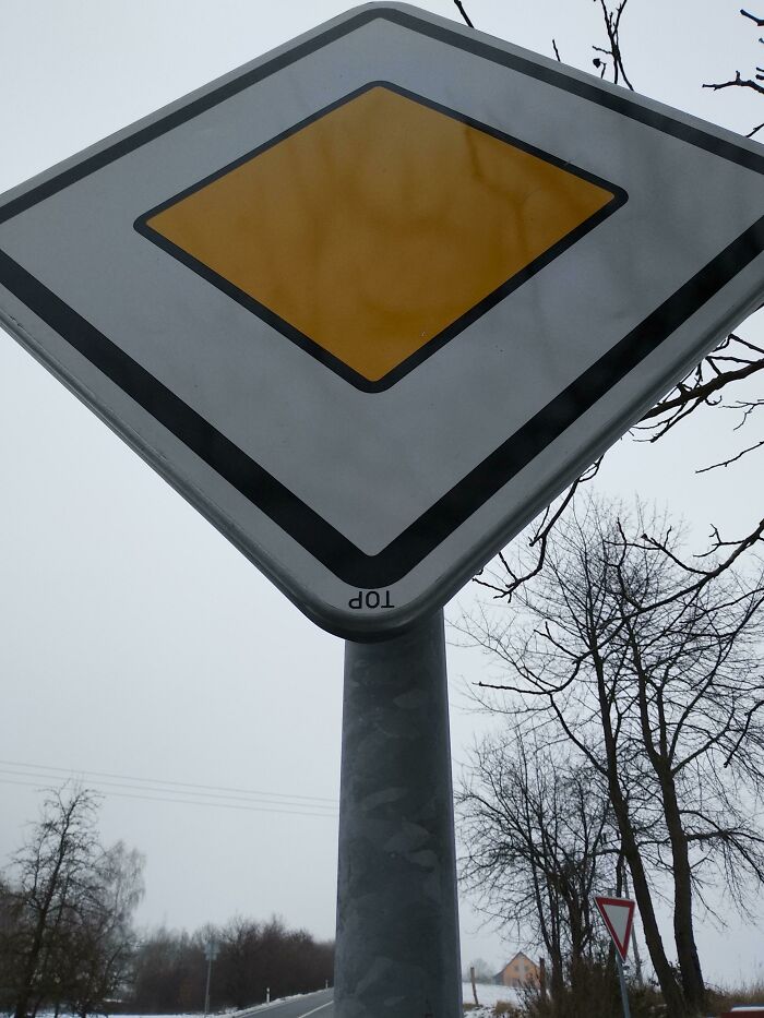 An upside-down European priority road sign, showing the word TOP inverted. A weird thing that needs fixing immediately.