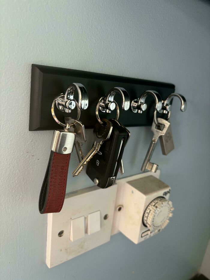 Keys hang from a key holder above two upside-down light switches and a timer. This is a weird upside-down thing.
