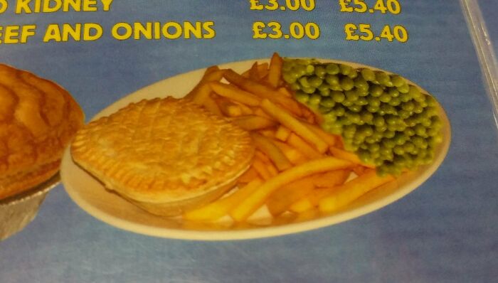 A meal with a golden-crusted pie, a pile of French fries, and green peas on a white plate, showing upside-down things on a menu.