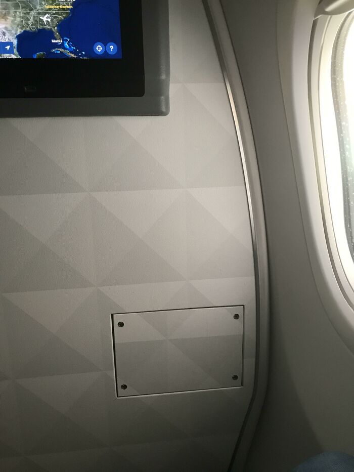 Airplane window view with an entertainment screen and textured wall, highlighting the weird upside-down things aspect.