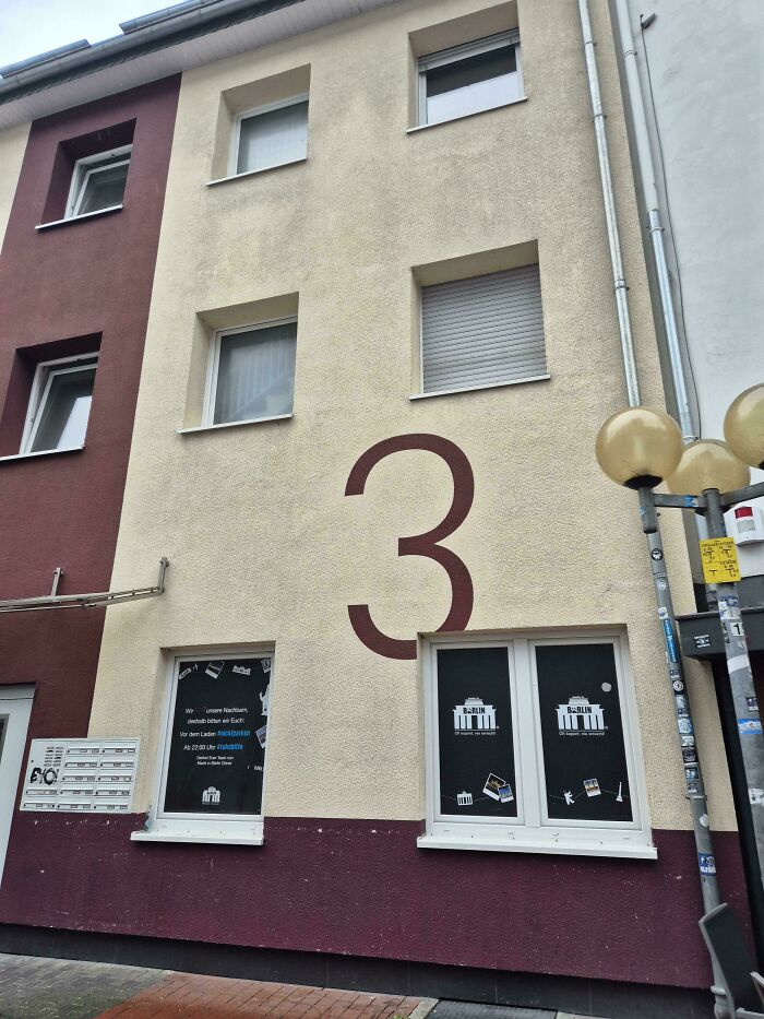 Upside-down things: a building with an unusually large number 3 painted, and windows below it displaying art.