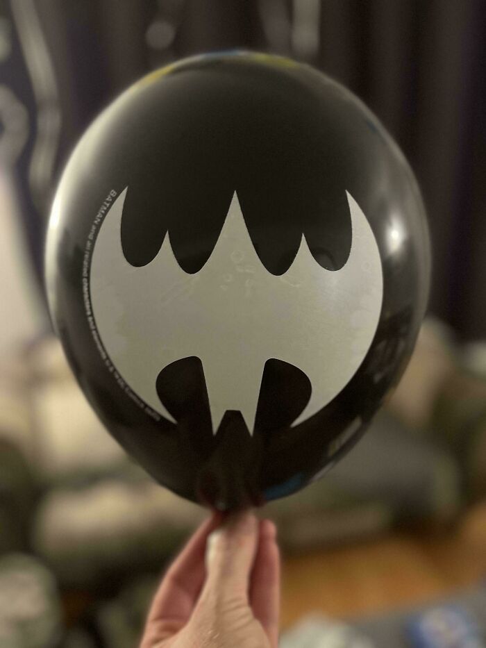 A hand holding an upside-down Batman balloon, showing the distinctive bat symbol. A weird upside-down thing.