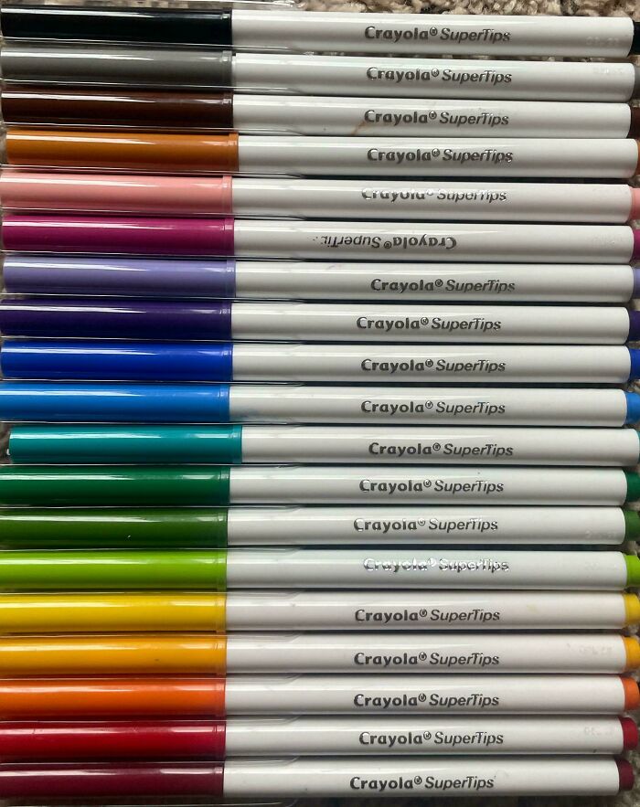 A row of Crayola SuperTips markers, mostly right side up, but some are upside-down things to be fixed.