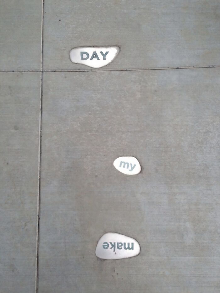 Three embedded words on a concrete path: DAY, MY, and an upside-down MAKE, exemplifying weird upside-down things.