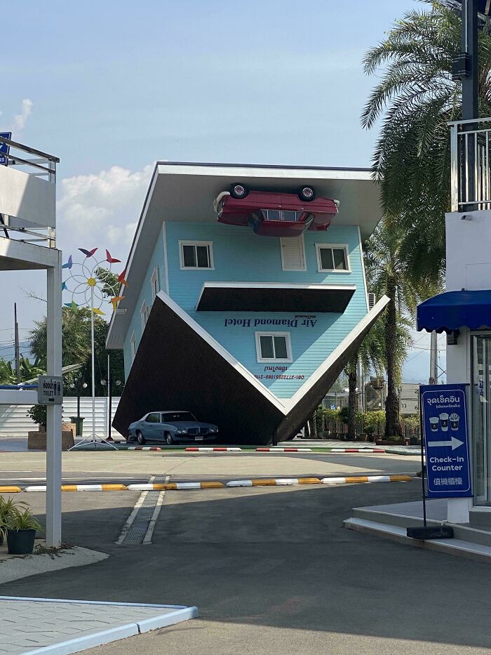 An upside-down house with a car mounted on its roof and another parked underneath, showcasing weird upside-down things.
