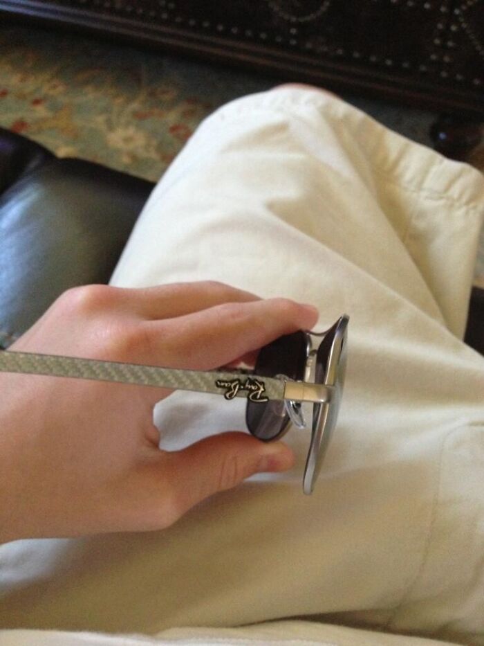 A hand holding Ray-Ban sunglasses, which appear upside-down, suggesting things to fix immediately.