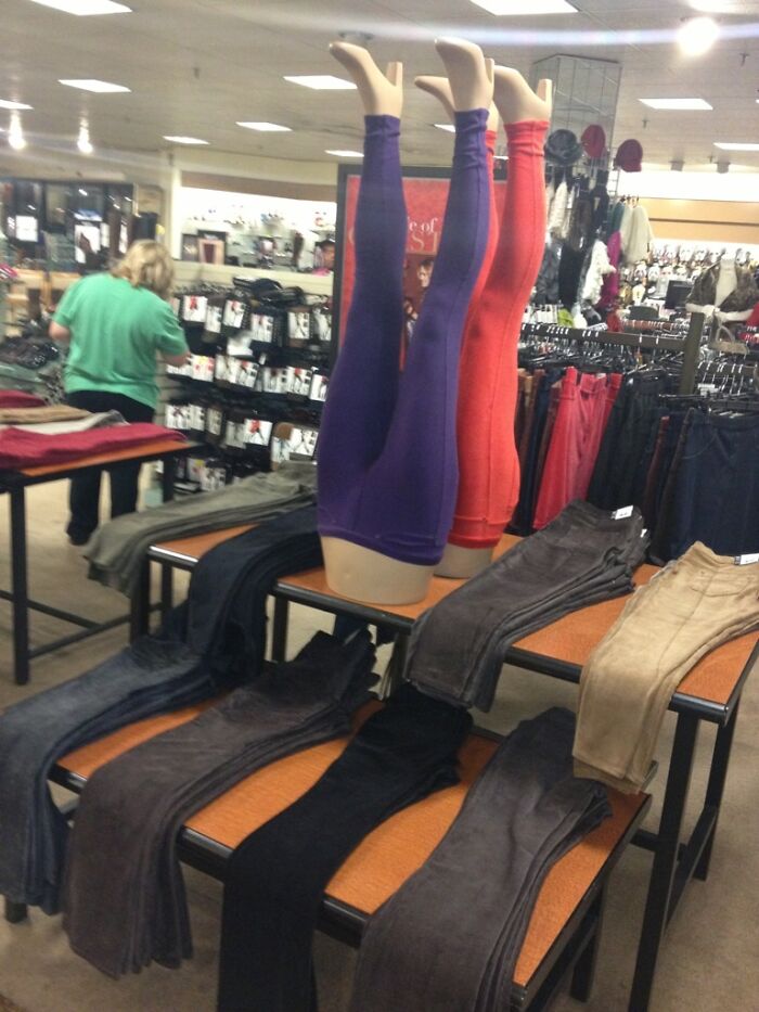 Two headless mannequins display upside-down leggings in a clothing store, one purple, one red, a weird sight.