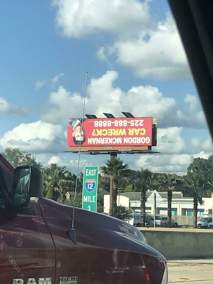 An upside-down billboard advertises Gordon McKernan's law firm for car wreck cases, showing his face inverted. Weird upside-down advertisement.