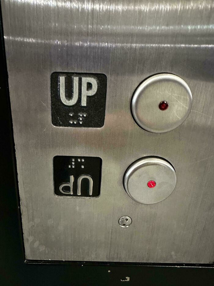 An elevator panel with an upside-down UP button, alongside a correctly oriented UP button. A weird upside-down thing that needs fixing.