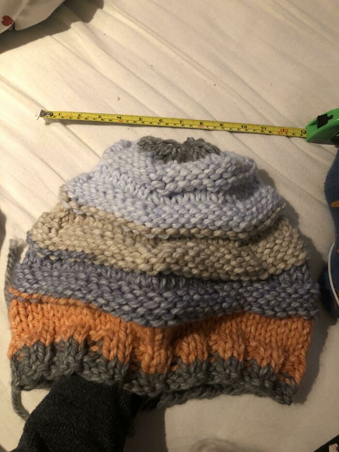 Thick knitted multicolor scarf with tape measure showing length, illustrating stories that sound made up but are 100% real.