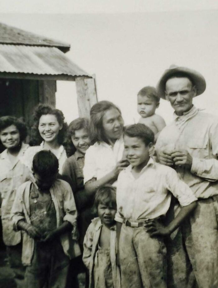 Black and white photo of a smiling family posing outdoors, capturing moments from decades ago in historic photos.