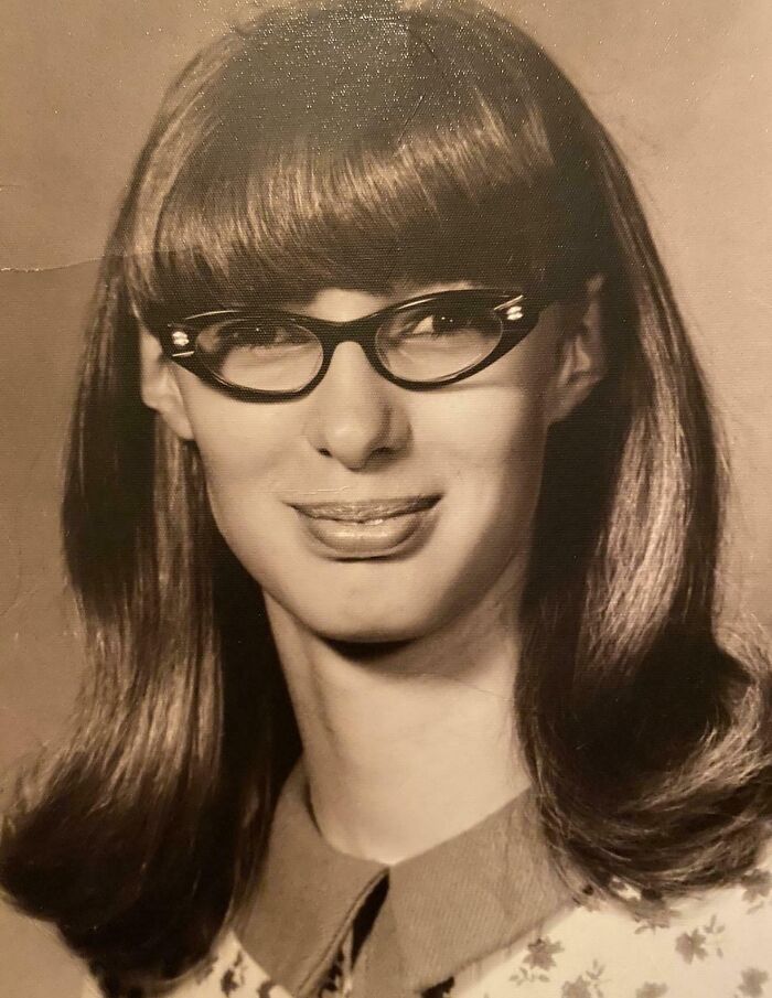 Vintage portrait of a young woman with cat-eye glasses and long hair, reflecting the charm of decades-old photos.
