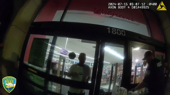 Police officers responding to a Walgreens entrance, capturing footage of a tense moment with a man inside the store.
