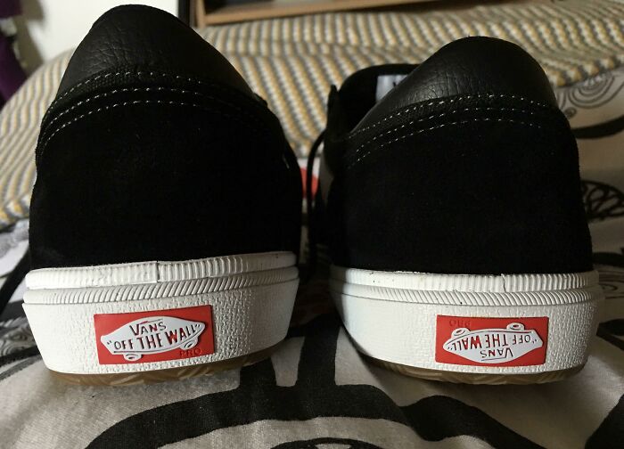 A pair of black Vans shoes from behind, one with the logo upside-down, a weird upside-down thing to fix immediately.