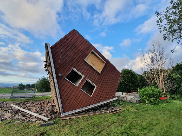 An upside-down house, angled into the ground with debris scattered, appearing as one of those weird things.