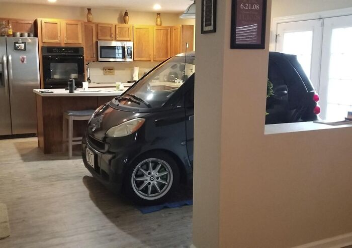 Small black car parked inside a kitchen area, illustrating unusual situations people gut warned about something wrong.