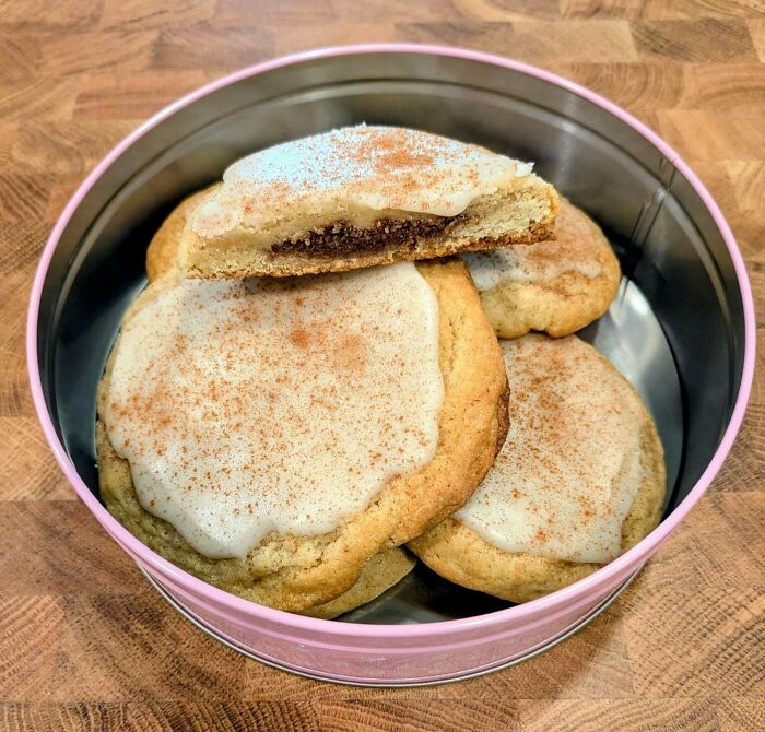 Frosted cookies with cinnamon sugar and a cookie cut in half showing filling