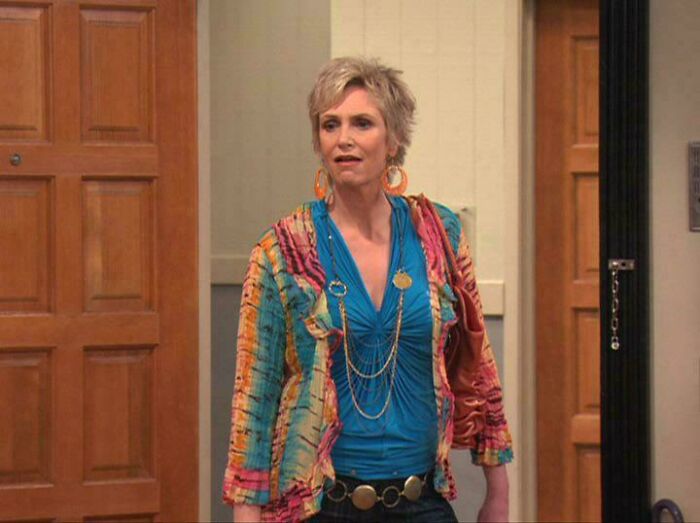 A woman with short blonde hair and a colorful jacket, showcasing nonsensical movie details.
