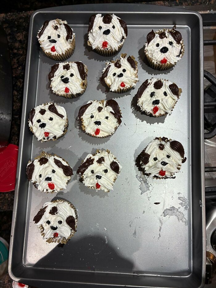 Cupcakes decorated to look like dog faces with icing on a baking tray