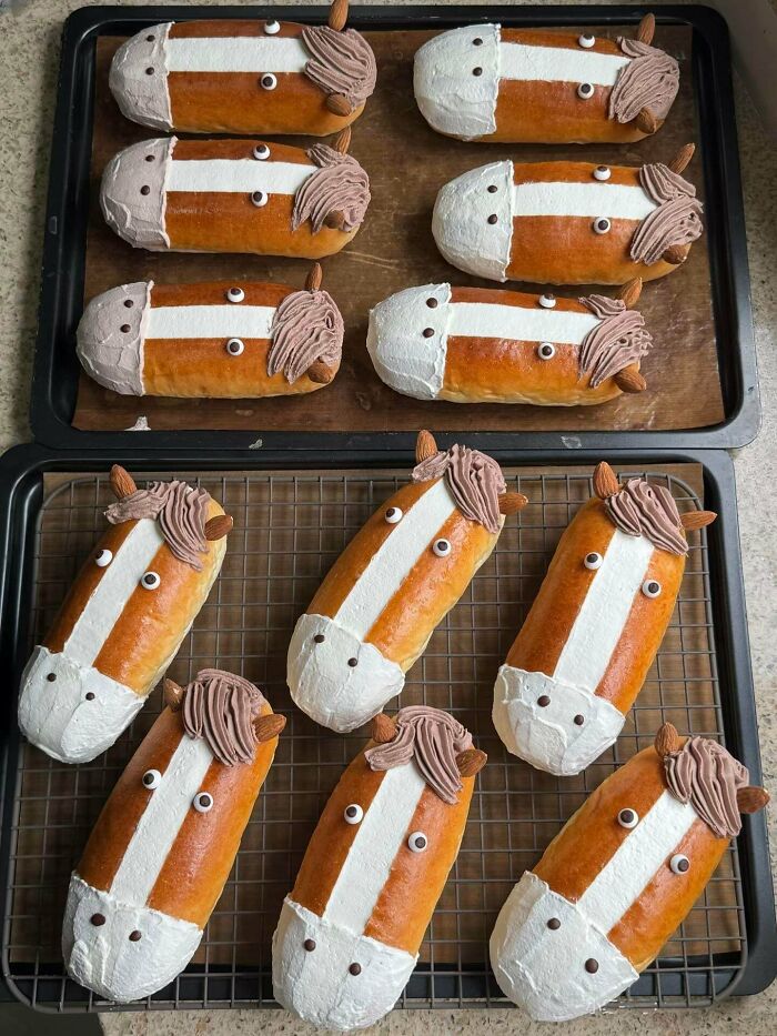 Horse-shaped dessert buns decorated with cream and almonds on baking trays