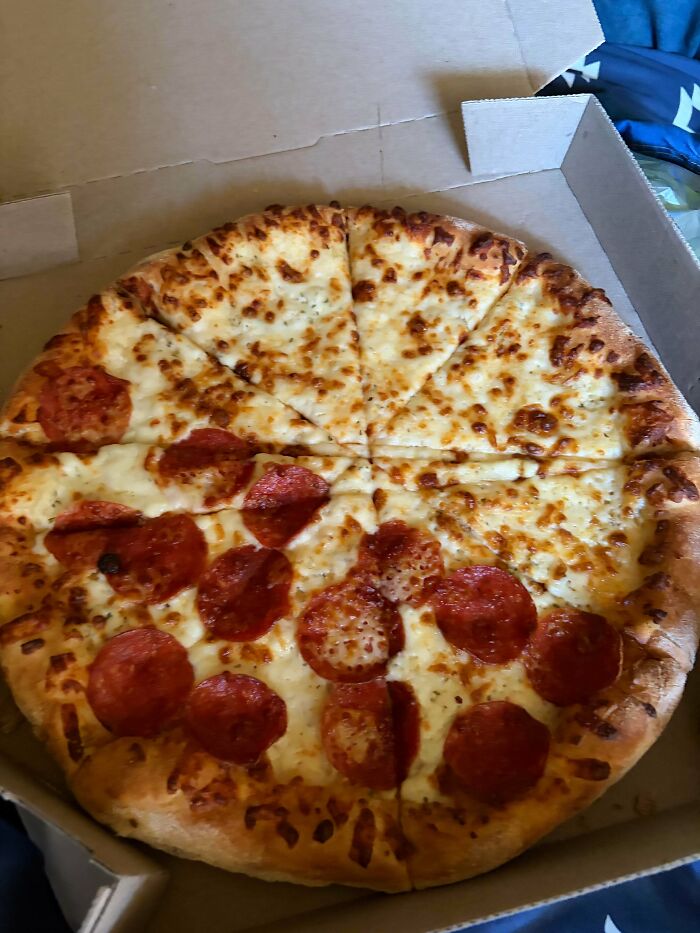 A pepperoni and cheese pizza with a clear divide, half pepperoni and half plain cheese, a funny You Had One Job fail.