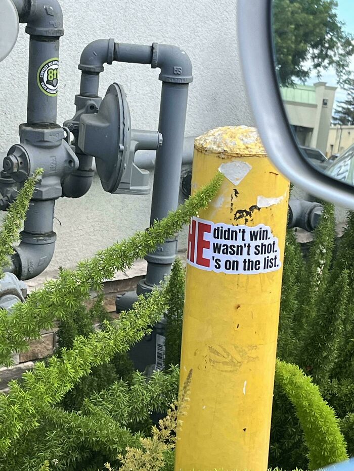 A yellow pole with a sticker that reads didnt win. wasnt shot. is on the list, a real life chaotic good post.