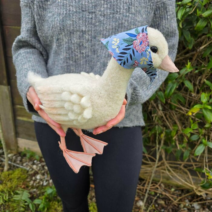 A person holding a charming handmade duck plushie wearing a bandana, a unique handmade project.