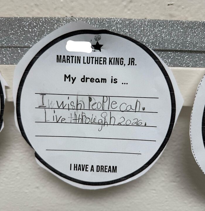 Child's handwritten note on Martin Luther King Jr. paper expressing hope to live through 2026, highlighting dystopian themes in the United States.