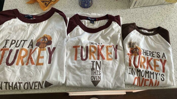 Three cringey parents shirts with turkey illustrations and text referencing pregnancy, laid on a counter.