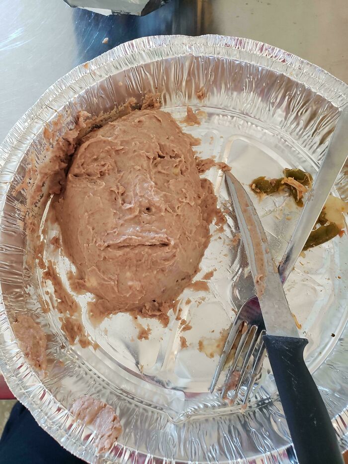 A mashed food substance in a foil container shaped like a face, a true bananasausage food crime.
