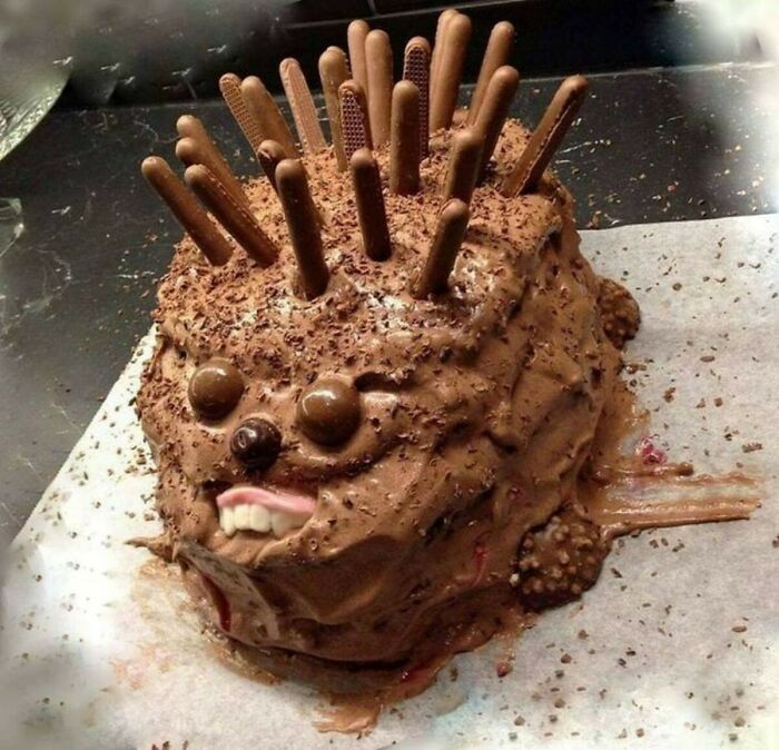 Chocolate cake resembling a hedgehog, decorated with chocolate sticks and a disturbing set of teeth. A Food Crime.