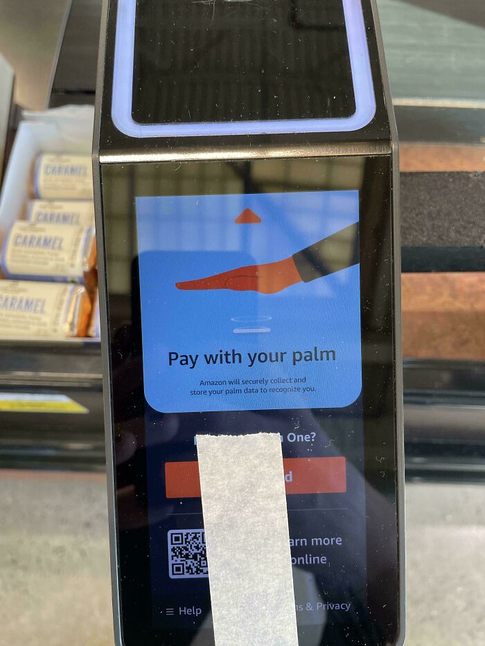Payment terminal displaying palm recognition technology, illustrating dystopian surveillance and biometric data use in the United States.