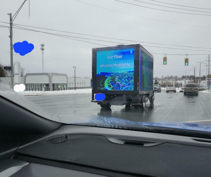 Dystopian United States street scene with digital billboard truck advertising AT&T fiber on a snowy day.