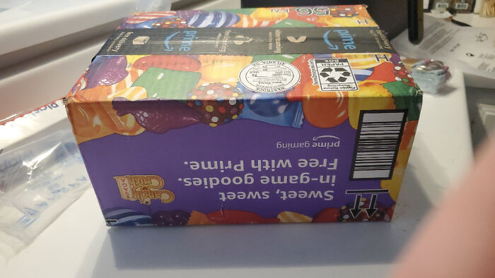 Colorful gaming-themed snack box, damaged and placed upside down on a cluttered white surface in a domestic setting.