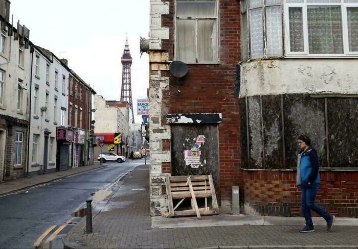 Run-down urban street with boarded-up windows and a pedestrian walking past