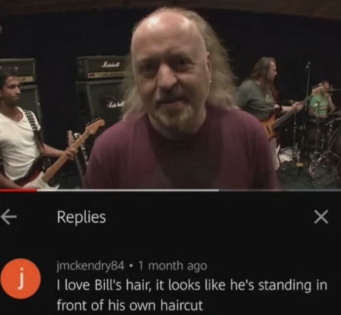 A bald man with long hair on the sides in a band setting, with a comment below delivering an epic burn about his haircut.
