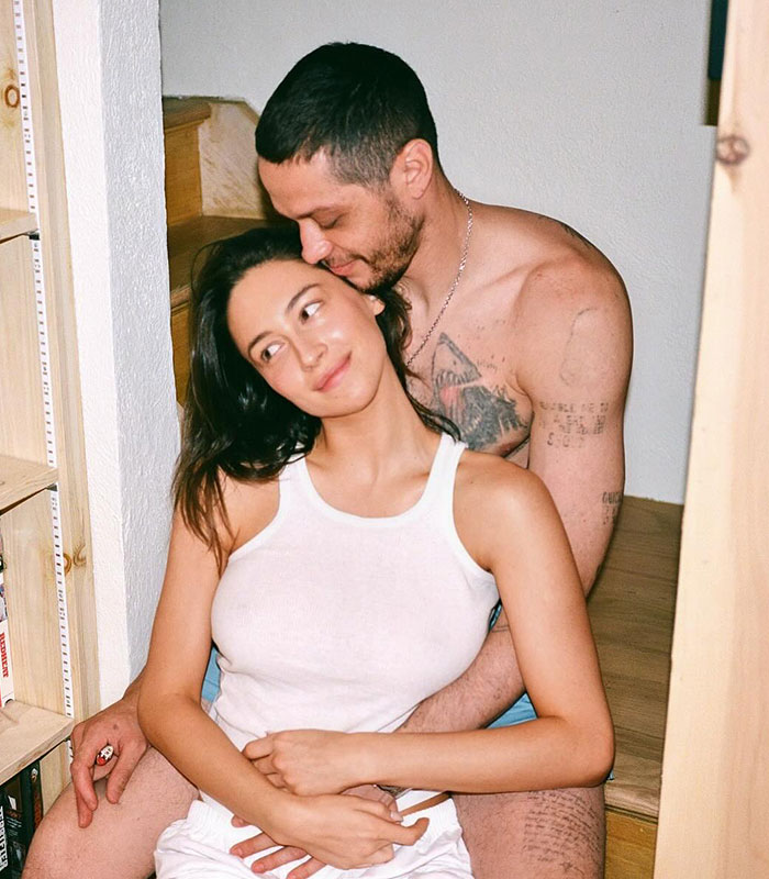 Pete Davidson and partner embracing affectionately at home, sparking debate about watching adult content after having a daughter.