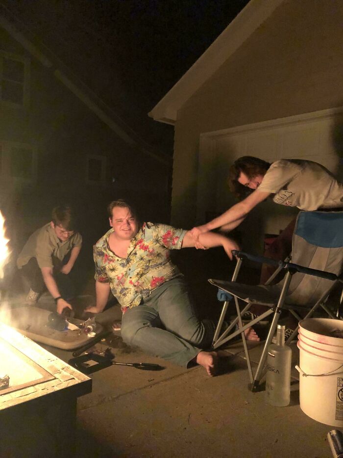 A chaotic backyard scene of friends by a fire pit, showcasing accidental Renaissance dynamics