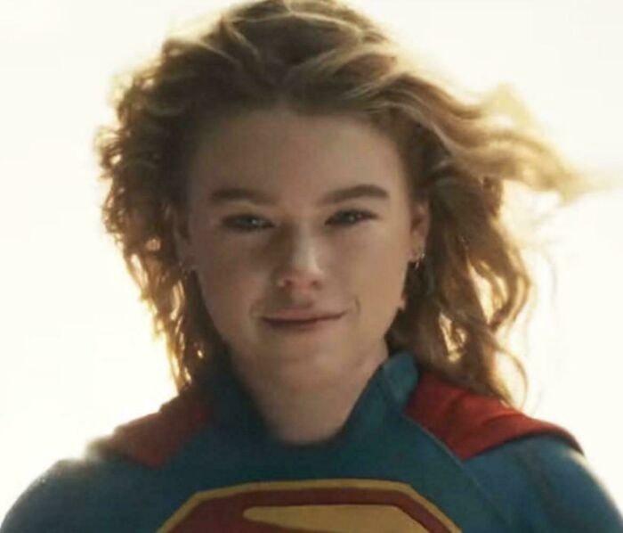 A young woman in a Supergirl costume, smiling, highlighting funny nonsensical movie details.