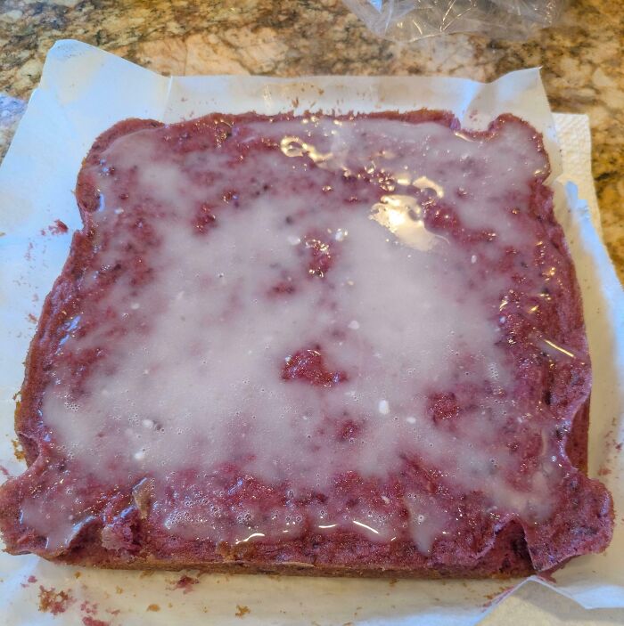 A red cake or Bananasausage with white glaze on paper, a food crime.