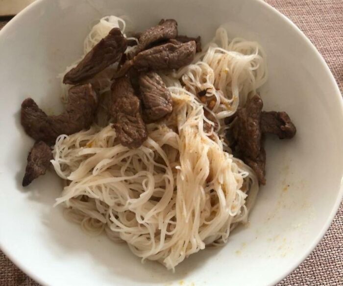 A white bowl of noodles and brown meat, possibly bananasausage, representing a food crime.