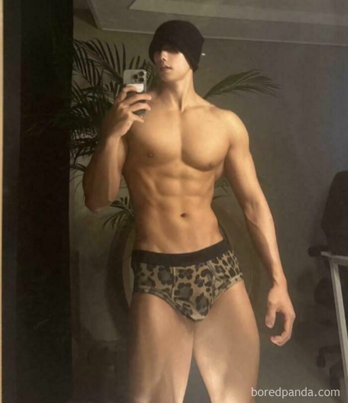 Muscular man in leopard print shorts taking a mirror selfie, showcasing wild Instagram edits and digital face alterations.