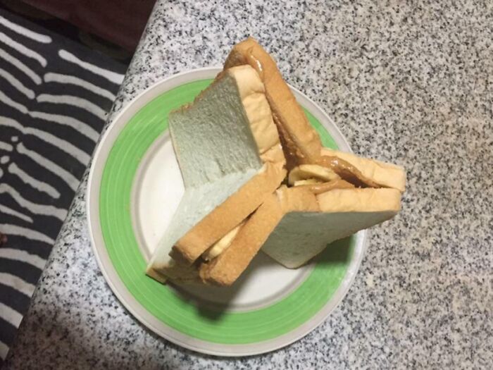 A messy bananasausage sandwich on a plate, featuring bread, peanut butter, and banana slices, a true food crime.