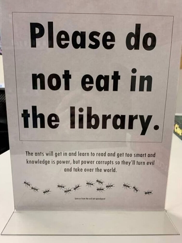 A sign reading "Please do not eat in the library," with humorous text explaining ants learning to read and take over the world. Oddly specific rules like these make you wonder.
