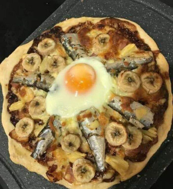 A pizza topped with bananas, sardines, and a fried egg, a true bananasausage food crime.
